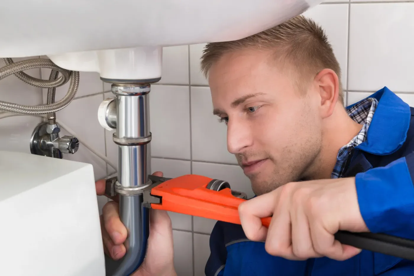 Plombier réparant le siphon d'un lavabo lors d'un dépannage à Paris (75)